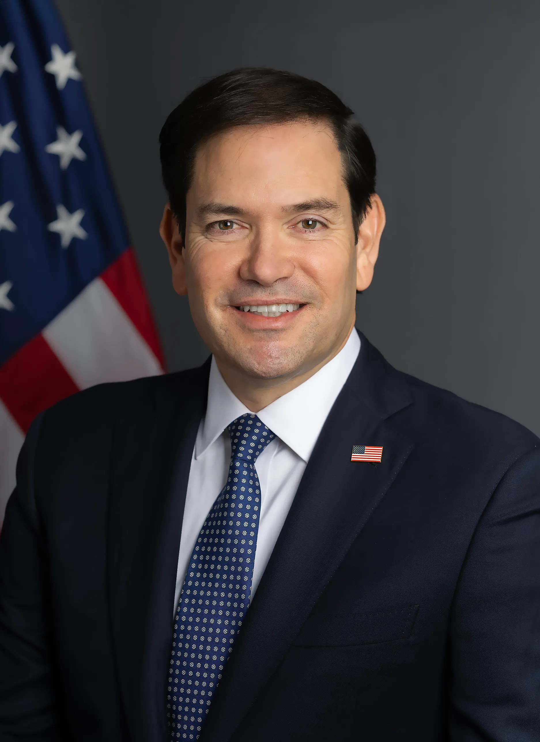 Marco Rubio i mörkblå kostym och blå slips framför en amerikansk flagga.
