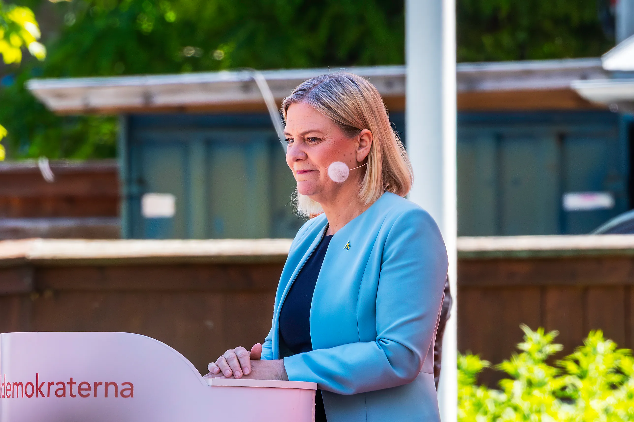 Magdalena Andersson i ljusblå kavaj står vid ett talarpodium med Socialdemokraternas namn på.