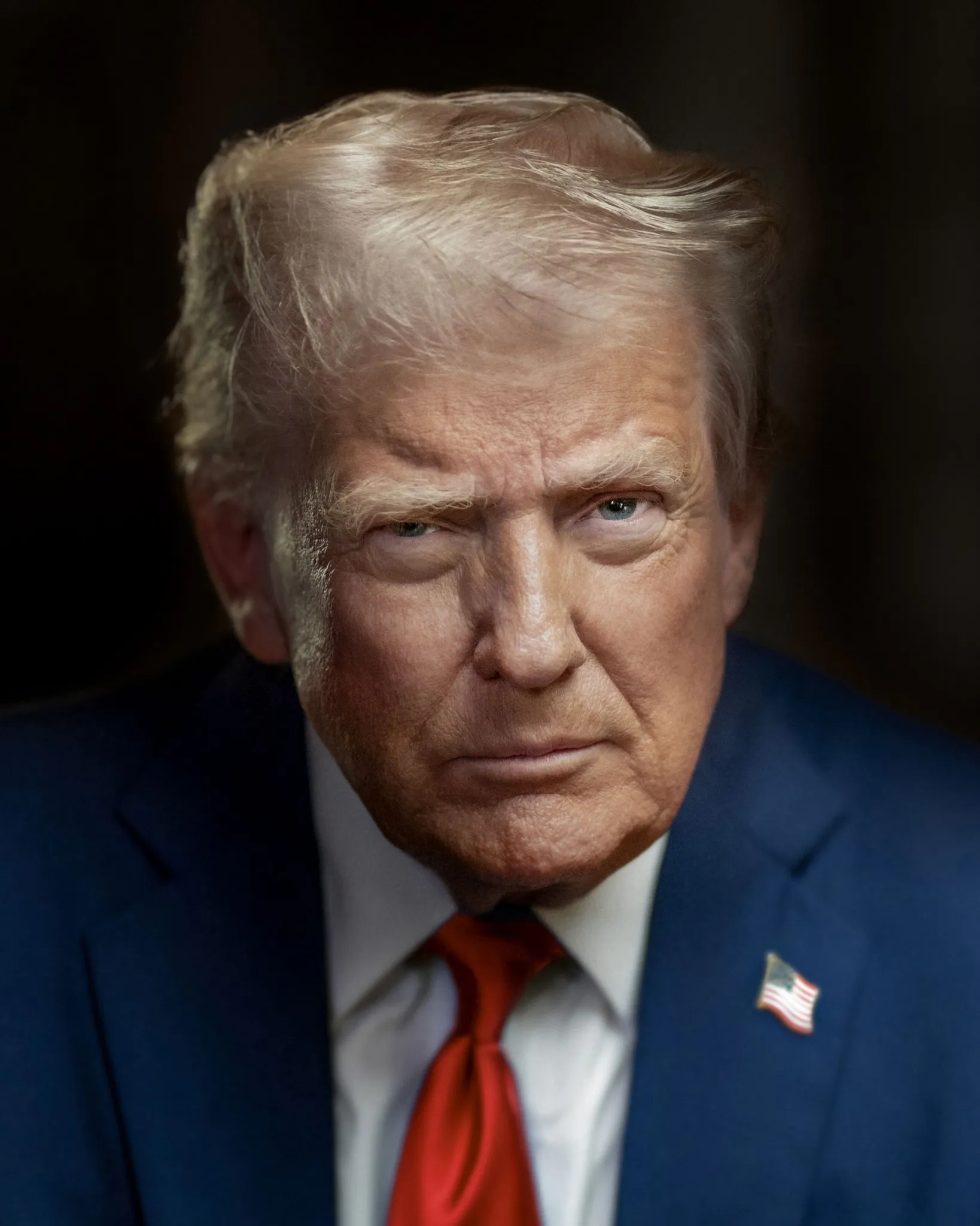 Donald Trump i mörkblå kavaj, vit skjorta och röd slips mot mörk bakgrund, med allvarlig blick mot kameran.